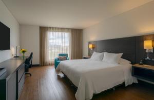 ein Hotelzimmer mit einem großen weißen Bett und einem Stuhl in der Unterkunft Hotel Morrison Usaquén in Bogotá