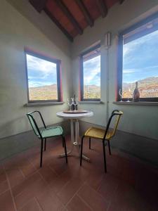 a table and two chairs in a room with two windows at La Torretta in Barga
