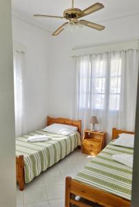 a bedroom with two beds and a ceiling fan at Emporios Blue Apartment in Emborios