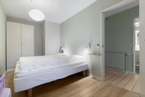 a white bedroom with a bed and a mirror at 84286-Ebeltoft-Ndr-Strandvej-3-M in Ebeltoft