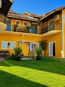 a yellow house with a yard with a swing at Villa das Calliandras in Chapada dos Guimarães