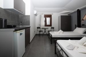 ein Zimmer mit zwei Betten und eine Küche mit einem Tisch in der Unterkunft Marlen Luxury Studios & Apartments in Platamonas