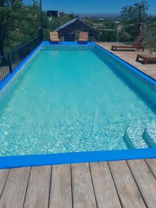 a swimming pool with blue water and a wooden deck at Cabañas Wasirumi Pileta y bajada al Rio in Bialet Massé