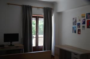 a room with a window with curtains and a television at apartamento 2000 in Algés +29 photos
