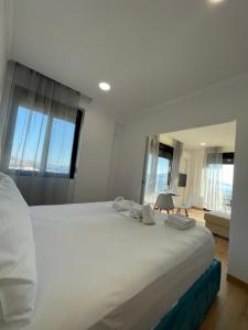a large white bed in a room with windows at Azzurre Premium Aparthotel in Sarandë