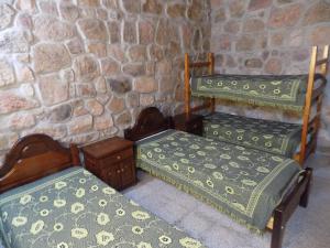 three beds in a room with a stone wall at Cabañas Wasirumi Pileta y bajada al Rio in Bialet Massé +20 photos