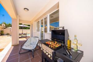 a barbecue with wine glasses and a chair next to a patio at Villa Dimi in Tsilivi