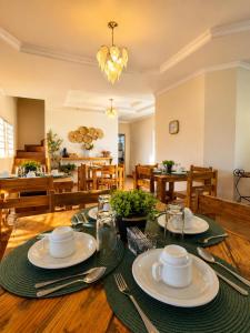 a dining room with a table with plates and silverware at Villa das Calliandras in Chapada dos Guimarães