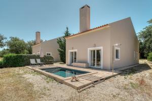 a villa with a swimming pool in front of a house at The Pink Stork Villa in Alcácer do Sal