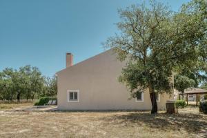 a white house with a tree in front of it at The Pink Stork Villa in Alcácer do Sal