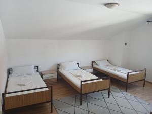 a room with three beds and a rug at Hostel Vera - Airport Podgorica in Podgorica