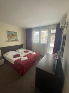 a hotel room with two beds and a desk at Peshev Family Hotel Nesebar in Nesebar
