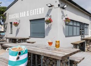 a wooden table with a glass of wine on a building at Coastal Escape Bude Resort in Bude