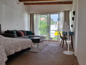 a bedroom with a bed and a couch and a window at Mi casa de campo Tlayacapan in Tlayacapan
