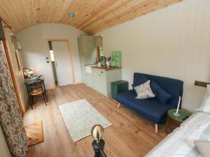 ein Wohnzimmer mit einer blauen Couch und eine Küche in der Unterkunft Cwtch Y Bugail 2 in Llandeilo