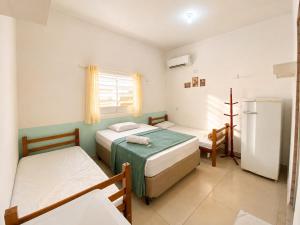a small room with two beds and a refrigerator at Pousada Pura Vida Bertioga in Bertioga