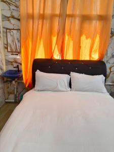 a bed with an orange curtain and a bed with white pillows at Arkan Motel Transit in Kampung Kuala Besut +12 photos