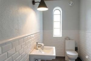 a white bathroom with a sink and a toilet at Gladeholm - Kivik - artist studio in Kivik