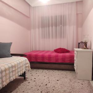 a bedroom with a pink bed and a window at The Vintage House in Nea Moudania
