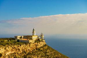 a lighthouse on a cliff next to the ocean at La LLar in Carboneras