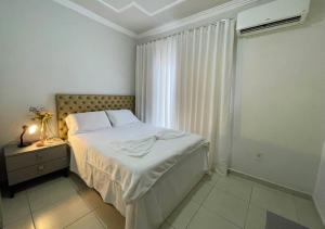 a white bedroom with a bed and a window at 474 Flats e Suítes Standard in Ipatinga