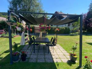 a table and chairs under a canopy in a garden at Cozy ground floor apartment in Xonrupt-Longemer +10 photos