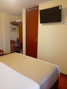 a bedroom with a bed with a flat screen tv on the wall at Hotel Santa Rosa in Arequipa