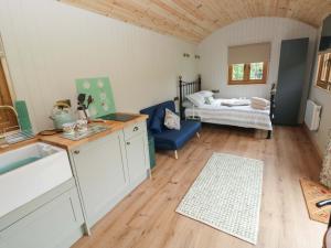 eine Küche mit Spüle und ein Wohnzimmer mit Bett in der Unterkunft Cwtch Y Bugail 1 in Llandeilo
