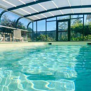 an indoor swimming pool with a pergola and blue water at Logis Hôtel & Restaurant Chateau de la Marjolaine in Essômes-sur-Marne