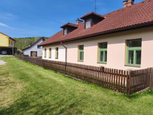 a house with a wooden fence in the yard at Pension V Doubí apartmán se sdílenou koupelnou in Slavče