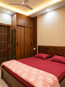 a bedroom with a bed with red sheets and wooden cabinets at The Elite Luxury Suite in Dehradun
