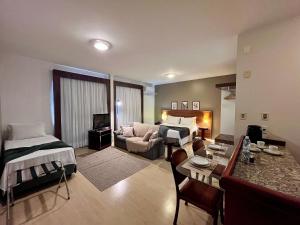 a room with a living room with two beds and a couch at Studio apartment in downtown Joinville, SC in Joinville
