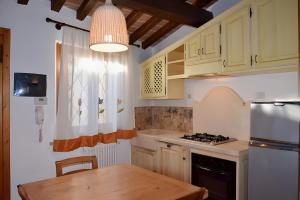 a kitchen with wooden cabinets and a table and aendant light at Il Cantinone A due passi dal mare in San Vincenzo