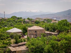 an old building in a village with mountains in the background at Mark B&B in Yeghegnadzor