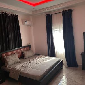 a bedroom with a large bed with black curtains at House 22 Apartments in Kubwa