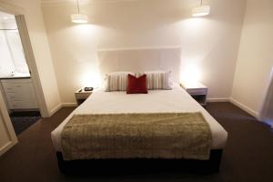 a bedroom with a large bed with two red pillows at Apartments by Townhouse in Wagga Wagga