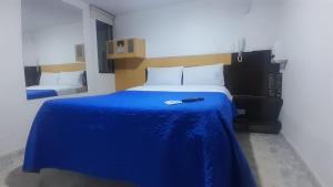 a bedroom with a bed with a blue blanket at Hotel Bonaire Un Estilo Difrente in Bogotá