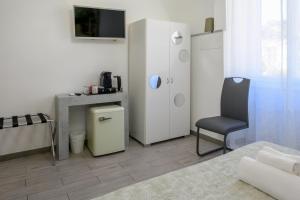 a room with a chair and a table and a refrigerator at SpeziAMo Rooms in La Spezia