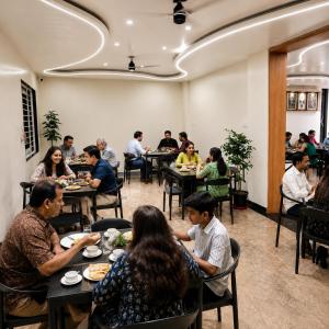 a group of people sitting at tables in a restaurant at The Sapphire Hotel in Belgaum