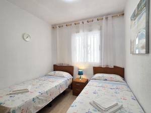two twin beds in a room with a window at Apartamento Trebol 2 in Oropesa del Mar +16 photos