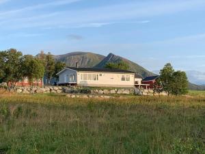a house in a field with mountains in the background at Roksoy for rent in Sortland +17 photos
