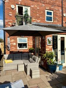 a patio with a couch and an umbrella at The Purrfect Creative Retreat in Gainsborough