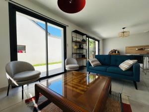 a living room with a blue couch and a glass table at Casa Avrillé in Avrillé