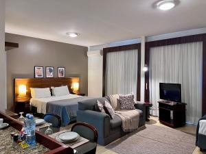 a hotel room with a bed and a couch at Studio apartment in downtown Joinville, SC in Joinville