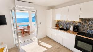 a kitchen with white cabinets and a view of the ocean at Villa Bilic in Rogoznica