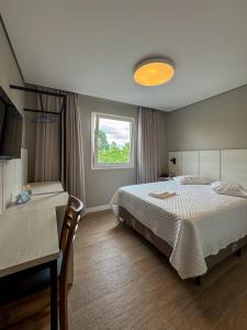 ein Schlafzimmer mit einem Bett, einem Tisch und einem Fenster in der Unterkunft Hotel Emacite Flex in Mafra