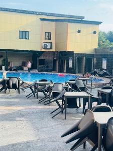 a pool with tables and chairs in front of a building at Goldstep hotel Okpaka in Warri