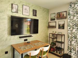 a dining room with a table and a flat screen tv at Студио Forest, к-с Нестинарка in Tsarevo