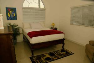 a bedroom with a bed with a red blanket at Caymanas Estate House in Portmore