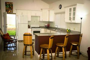 una cocina con armarios blancos y una barra con taburetes en Caymanas Estate House, en Portmore